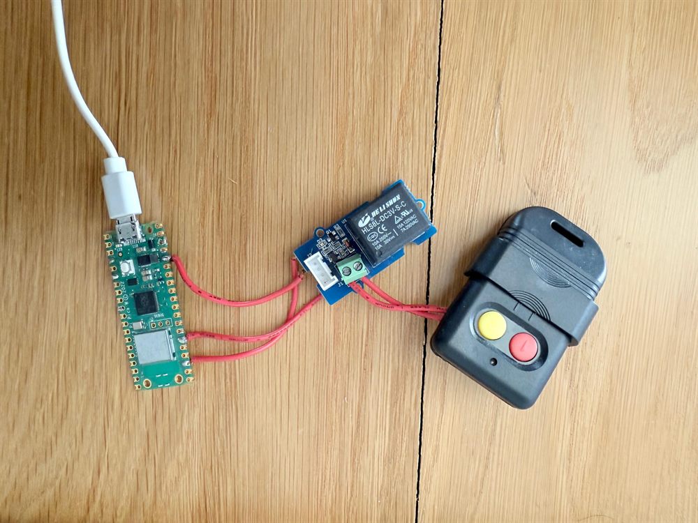 A Raspberry Pi Pico W wired through a single-channel relay to the contacts of a 330 MHz gate remote